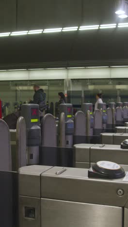 Vídeo-Vertical-De-Pasajeros-En-La-Barrera-De-Billetes-En-La-Estación-De-Metro-Canary-Wharf-Docklands,-Londres,-Gran-Bretaña.